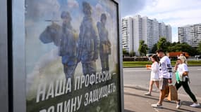 Des gens passent devant une affiche promouvant le service militaire sous contrat et sur laquelle on peut lire "Notre travail, défendre la patrie", à Moscou, le 4 septembre 2023.