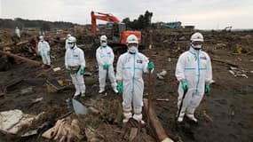 Policiers à la recherche de corps à Minamisoma, dans la préfecture de Fukushima, observant une minute de silence en hommage aux victimes du séisme et du tsunami qui a frappé le nord-est du Japon il y a un mois jour pour jour. Le gouvernement japonais a an