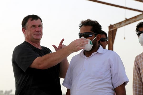 Un membre de l'ONU montre à un homme comment utiliser un masque de protection, alors qu'il forme une équipe locale à l'utilisation d'un barrage flottant pour protéger la côte d'un déversement de pétrole du FSO Safer, au Yémen, le 13 juillet 2023.