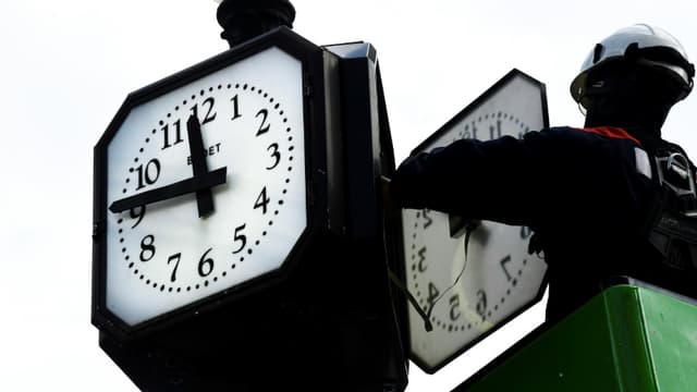 Un agent effectue manuellement le changement d'heure à l'heure d'été sur une horloge à Paris, le 26 mars 2021