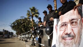Policiers égyptiens devant la Cour constitutionnelle à côté d'un portrait du président Mohamed Morsi, au Caire. Avec la proclamation officielle des résultats du référendum sur la Constitution, le pouvoir égyptien espère clore mardi des mois de troubles po