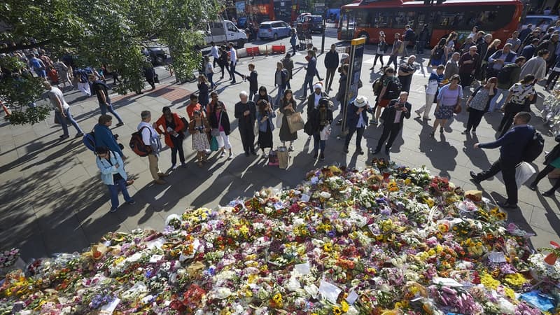 Des piétons s'arrêtent pour observer les fleurs déposées en mémoire des victimes de l'attaque terroriste du 3 juin à Londres (Royaume-Uni), le 9 juin 2017.
