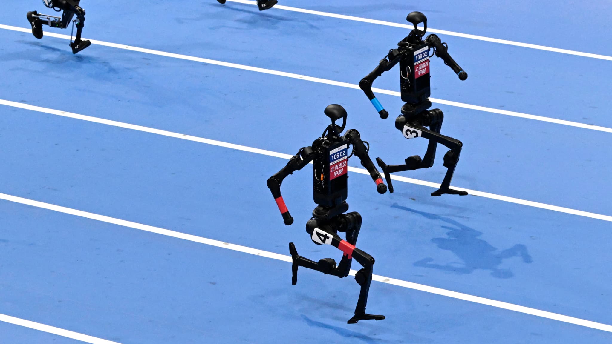 Un robot humanoïde court aux côtés d'un autre robot lors de la finale du 100 mètres à l'occasion des Jeux mondiaux de robots humanoïdes, le 17 août 2025 à Pékin, en Chine (photo d'illustration).