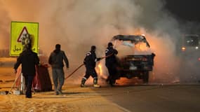 Des pompiers tentent d’éteindre un véhicule en feu aux abords du stade où se sont déroulés les graves incidents de dimanche