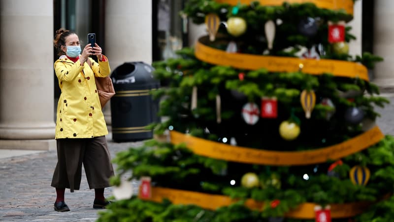 Touriste face à un sapin de Noël à Londres.