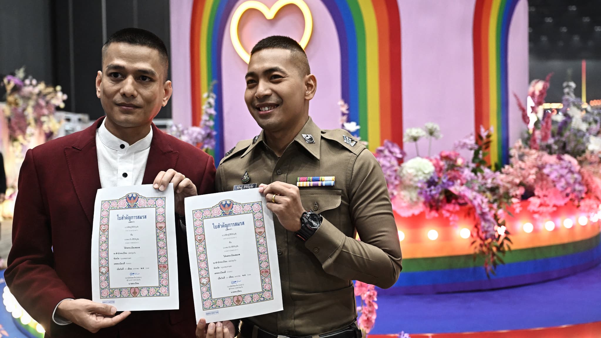 Un couple pose avec son certificat lors d'une cérémonie de mariage au centre commercial Paragon à Bangkok, en Thaïlande, le 23 janvier 2025.