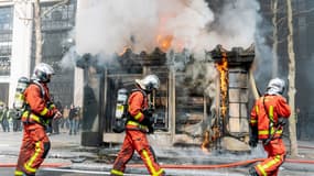 Des pompiers devant l'incendie d'un kiosque sur les Champs-Élysées, le 16 mars 2019