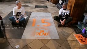Une photo du groupe Just Stop Oil montrant deux militantes écologistes assises à côté de la tombe de Charles Darwin, après avoir pulvérisé "1.5 is dead" sur celle-ci, à l'intérieur de l'abbaye de Westminster, à Londres, le 13 janvier 2025.
