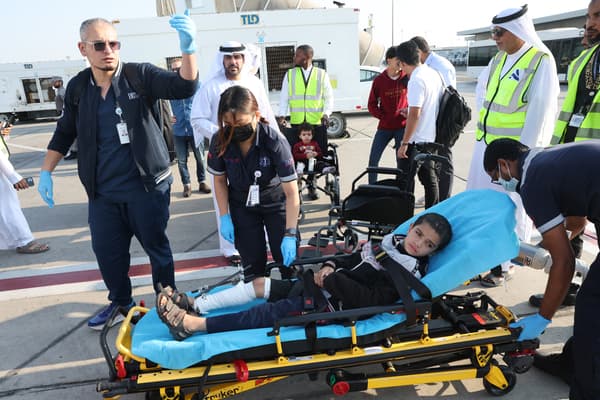 Wolontariusze wynoszą ranne palestyńskie dziecko z samolotu po jego przybyciu do Abu Zabi 18 listopada 2023 r., po jego ewakuacji z Gazy w ramach misji humanitarnej zorganizowanej przez Zjednoczone Emiraty Arabskie.