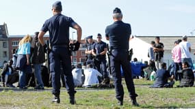 Les forces de l'ordre surveillent des migrants après qu'une distribution de nourriture a viré à l'affrontement, le 5 août 2014.