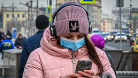 Une femme marche dans la rue en regardant son smartphone, à Moscou