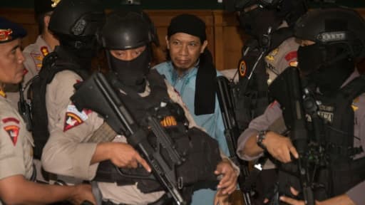 Des policiers de l'anti-terrorisme escortent le 22 juin 2018 à Jakarta le prédicateur indonésien Aman Abdurrahman (C) après sa condamnation à la peine capitale pour avoir ordonné les attentats suicide dans la capitale indonésienne en 2016 Des policiers de l'anti-terrorisme escortent le 22 juin 2018 à Jakarta le prédicateur indonésien Aman Abdurrahman (C) après sa condamnation à la peine capitale pour avoir ordonné les attentats suicide dans la capitale indonésienne en 2016