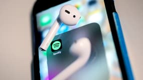 Un smartphone affichant l'application Spotify, ainsi que des AirPods