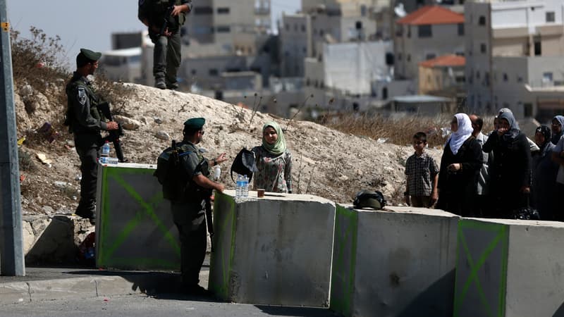 Des garde-frontières israéliens contrôlent des Palestiniens à un check-point matérialisé par des blocs de béton barrant la route, près du quartier arabe d'Essaouiya, à Jérusalem, le 16 octobre. 