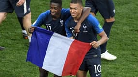 Ousmane Dembélé et Kylian Mbappé posent avec le drapeau français après la victoire en finale de la Coupe du monde le 15 juillet 2018 à Moscou