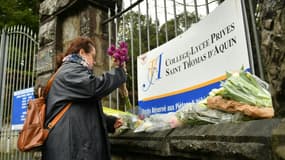 Des personnes déposent des bouquets en hommage à la professeure d'espagnol assassinée devant le lycée dans lequel elle enseignait à Saint-Jean-de-Luz, dans les Pyrénées-Atlantiques, le 23 février 2023