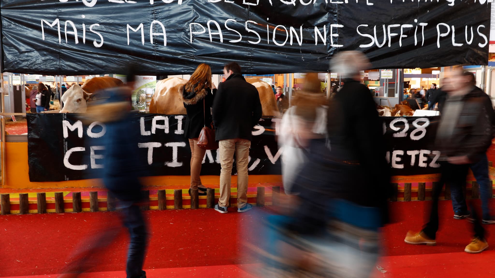 Des visiteurs devant une banderole réclamant une revalorisation de la rémunération des agriculteurs lors du Salon de l'agriculture, le 27 février 2016.