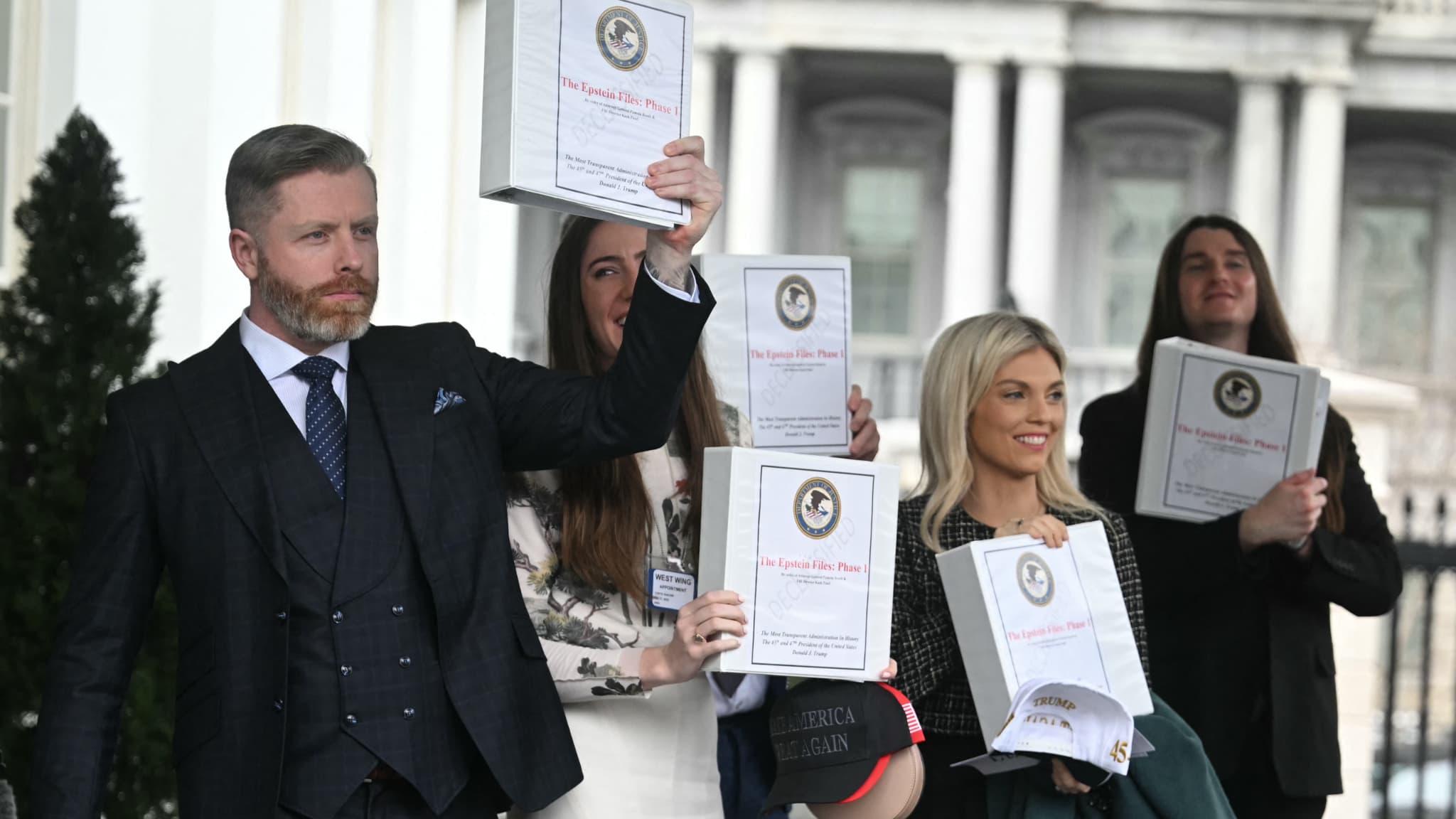 Des influenceurs conservateurs américains sortent de la Maison Blanche en brandissant la "phase 1" du dossier Epstein, le 27 février 2025 à Washington D.C.