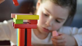 Une enfant joue avec des dominos colorés (photo d'illustration)