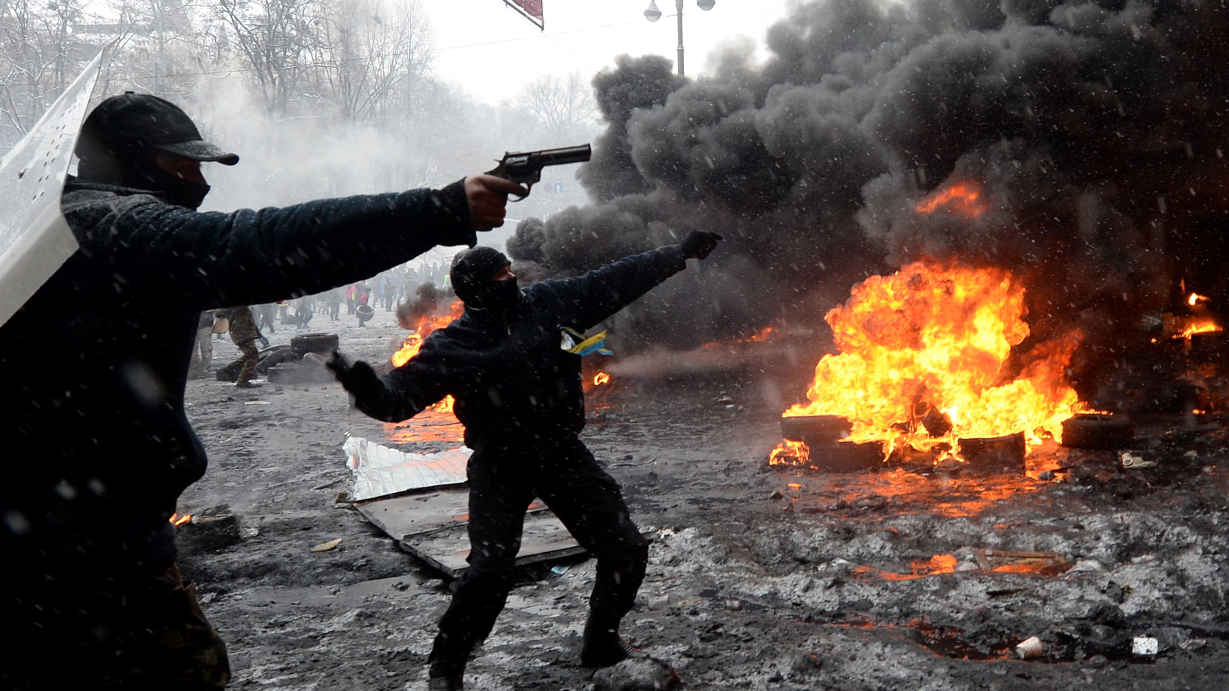 Un manifestant point un pistolet sur les policiers, mercredi 22 janvier, à Kiev.