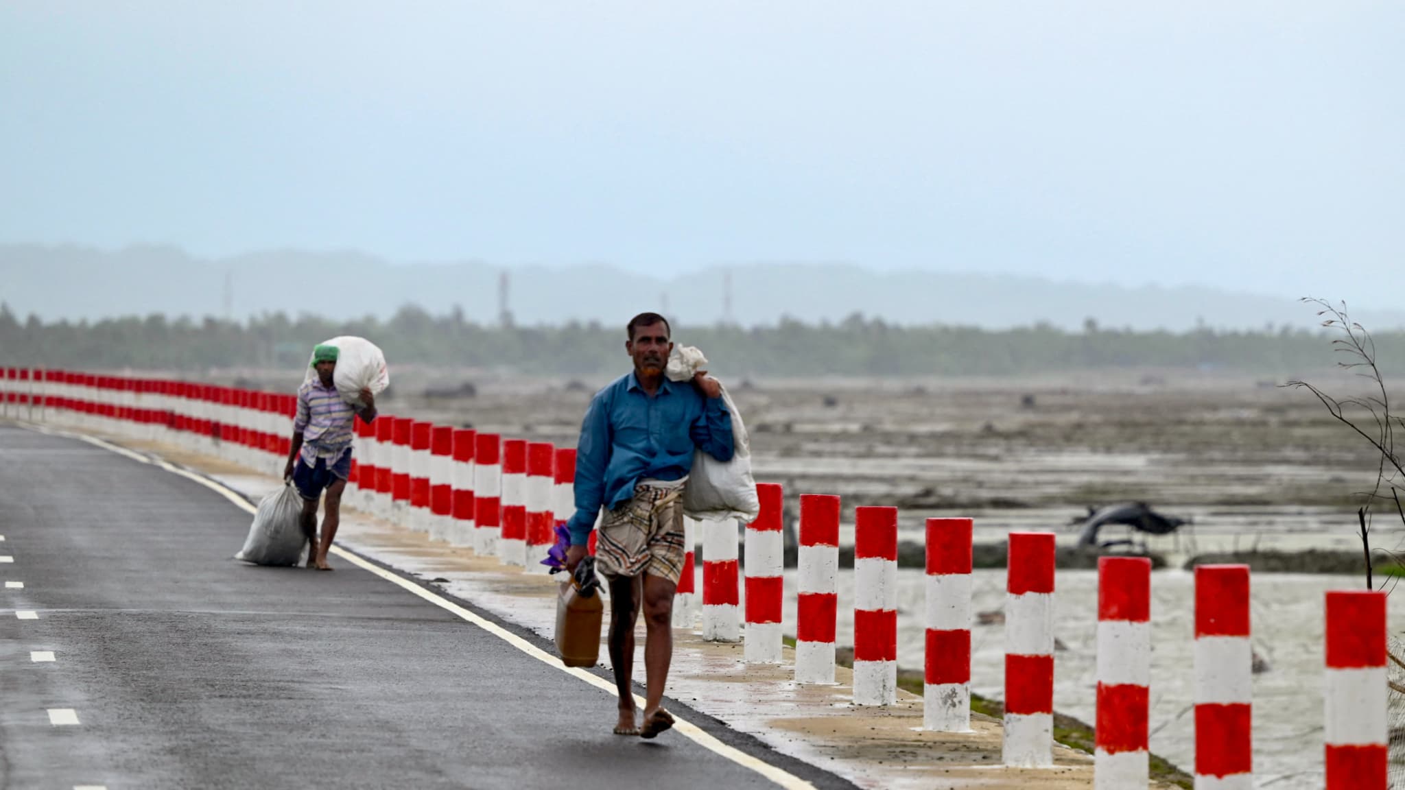 Des hommes partent sur les routes avec leurs affaires pour se mettre à l'abri au passage du cyclone Mocha sur l'île Shapori au Bangladesh, le 14 mai 2023 Des hommes partent sur les routes avec leurs affaires pour se mettre à l'abri au passage du cyclone Mocha sur l'île Shapori au Bangladesh, le 14 mai 2023