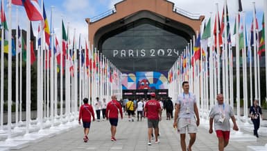 Les participants aux Jeux Olympiques et Paralympiques de Paris 2024 marchent devant la cafétéria du Village Olympique, à Saint-Denis, le 22 juillet 2024.
