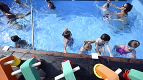 Des enfants prennent une leçon de natation avec des maîtres-nageurs dans une piscine, le 13 juillet 2022. (Illustration)