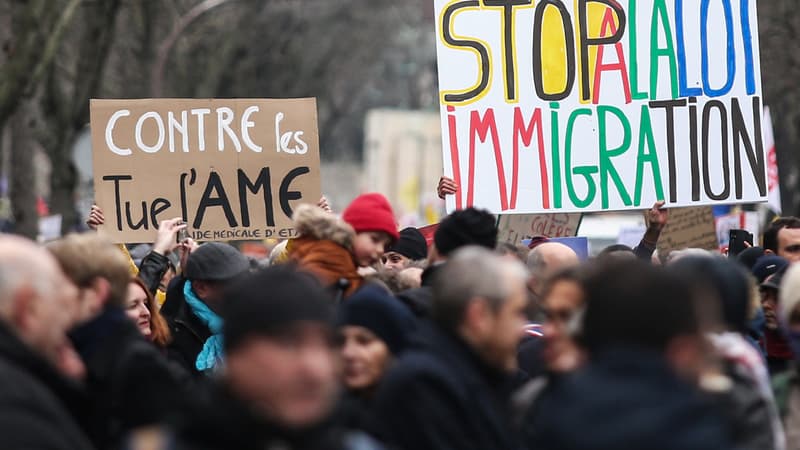 Des manifestants brandissent des pancartes alors qu'ils participent à un rassemblement contre la loi sur l'immigration récemment adoptée par la France, à Paris le 21 janvier 2024. 