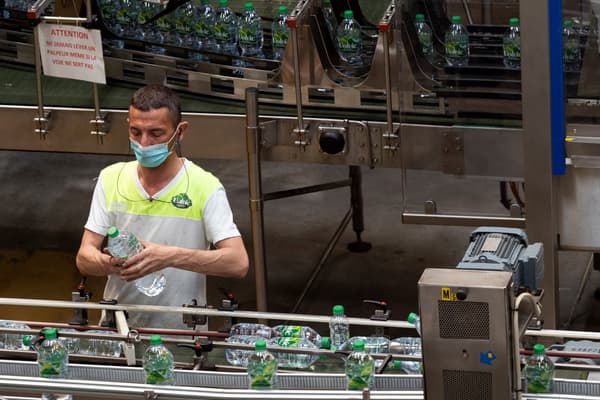 Un ouvrier masqué sur une ligne de production de l'usine Volvic en mai 2021.