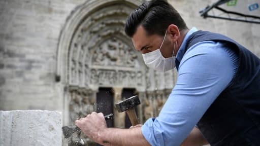 Un tailleur de pierre  montre les gestes médievaux devant des visiteurs dans le cadre d'un atelier et du projet de reconstruction de la flèche de la basilique Saint-Denis, devant l'édifice à Saint-Denis, le 5 juin 2020