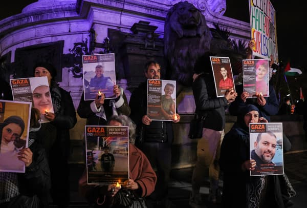 Des manifestants tiennent des bougies et des pancartes, avec des portraits de victimes des batailles en cours entre Israël et le groupe palestinien Hamas, sur lesquelles on peut lire "Gaza, des visages, pas seulement des chiffres" lors d'un rassemblement "en solidarité avec le peuple palestinien" place de la République à Paris, le 2 novembre 2023.