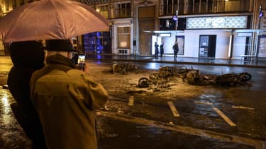 Des passants prennent en photo des scooters brûlés au milieu des rues de Paris le 8 décembre 2018
