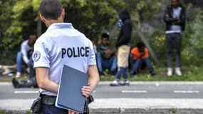 Un policier regarde les migrants qui attendent au bord de la route près du port de Calais le 16 août 2017 (image d'illustration)