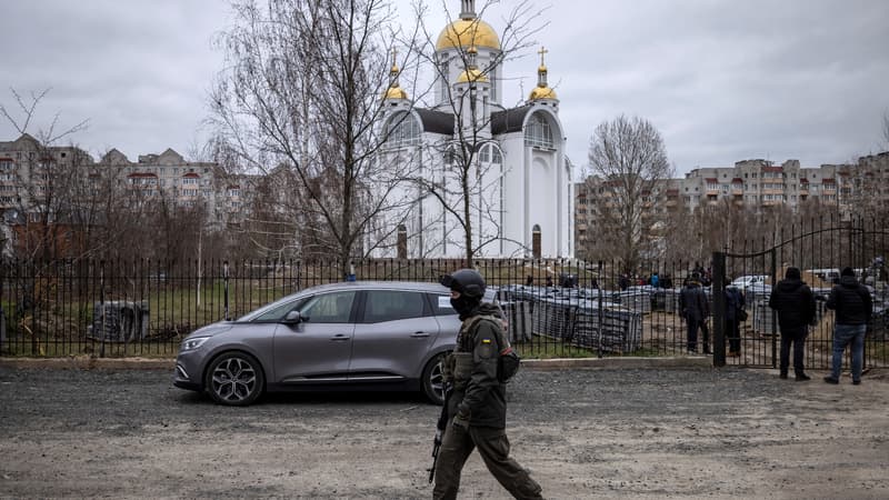 Un soldat ukrainien passe devant l'église Saint-André à Boutcha en Ukraine, le 13 avril 2022