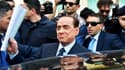 L'ancien chef du gouvernement italien Silvio Berlusconi quitte un bureau de justice de Milan, le 23 avril 2014, entouré de ses gardes de sécurité.