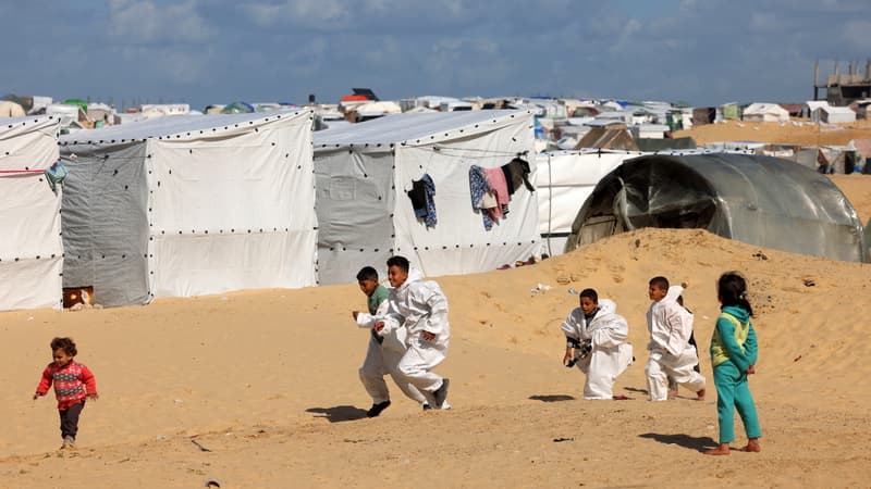 Les combinaisons Hazmat, vestiges de la pandémie de coronavirus, sont portées par des enfants palestiniens déplacés pour se garder au chaud, alors qu'ils jouent dans un camp de fortune installé sur la plage de Rafah, dans la bande de Gaza, le 31 janvier 2024, au milieu des combats en cours entre Israël et Israël.