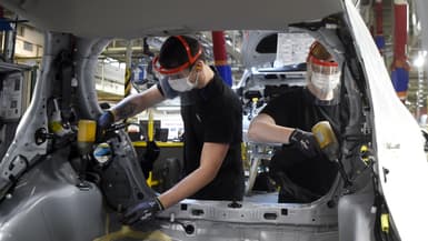 Les employés de Toyota portent des masques et des gants de protection lorsqu'ils travaillent sur des véhicules sur la chaîne de montage de l'usine automobile Toyota à Onnaing, près de Valenciennes, le 23 avril 2020, alors que l'usine a rouvert après plus d'un mois d'interruption visant à freiner la propagation du COVID-19.