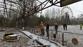 Des visiteurs marchent dans un parc d'attractions abandonné dans la ville fantôme de Pripyat, non loin de la centrale nucléaire de Tchernobyl, le 8 décembre 2020.