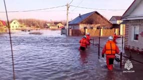 Des sauveteurs évacuent des habitants dont les maisons ont été inondées après la rupture partielle d'un barrage à Orsk, dans la région d'Orenbourg, en Russie, le 6 avril 2024