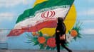 Une femme voilée passe devant un drapeau iranien dans une rue de Téhéran, en Iran, le 11 octobre 2022
