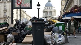 Des piétons passent devant des poubelles à Paris, avec le Panthéonen arrière-plan, le 20 mars 2023.