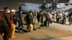 Des Français et des Afghans attendent pour embarquer à bord d'un avion de transport militaire français le 17 août 2021 à l'aéroport de Kaboul