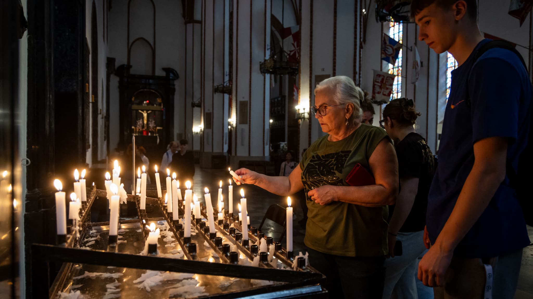Une femme allume une bougie dans la cathédrale Saint-Jean, dans la vieille ville de Varsovie, le 21 avril 2025, en hommage au pape décédé ce même jour.