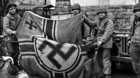 Des soldats anglais tenant un drapeau nazi au moment de la libération