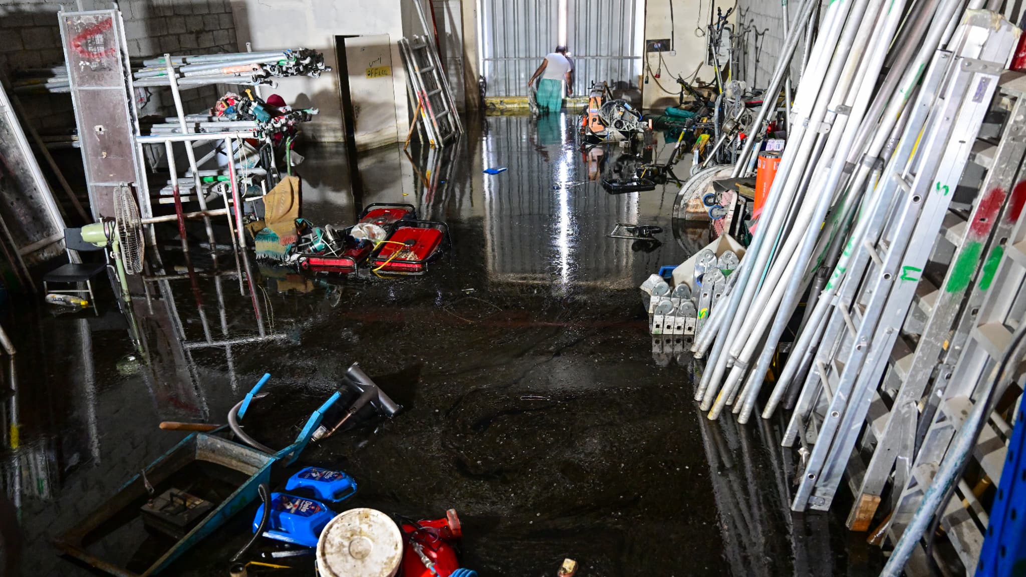 Un homme traverse un entrepôt inondé à Dubaï suite à de fortes pluies, le 18 avril 2024.
