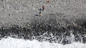 Des promeneurs sur la plage où a été retrouvé le débris d'avion