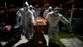 Des employés des pompes funèbres transportent le cercueil d'une personne décédée du coronavirus, le 30 mai 2020 au cimetière de Breves, au Brésil