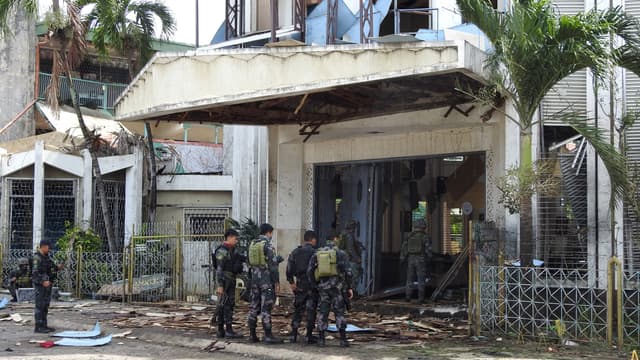 Des policiers et militaires se tiennent devant une cathédrale de l'île de Jolo, dans les Philippines, après l'explosion de deux bombes le 27 janvier 2019.