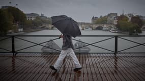 Une personne s'abrite sous un parapluie en traversant le pont des Arts durant la dépression Kirk qui provoque de fortes pluies sur le centre de Paris, le 9 octobre 2024. 