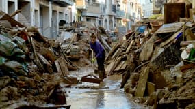 Une femme tente d'évacuer des débris d'une rue de Paiporta, en Espagne, le 6 novembre 2024